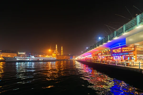Ponte di Galata con i pescatori sopra e i ristoranti sotto il ponte con luci al neon — Foto Stock