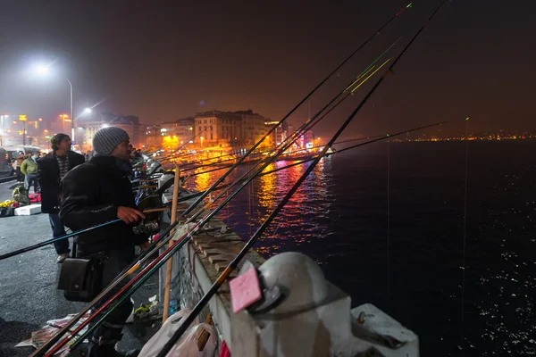 Pescadores locais pescando na Ponte Galata à noite que atravessa o Chifre de Ouro em Istambul — Fotografia de Stock