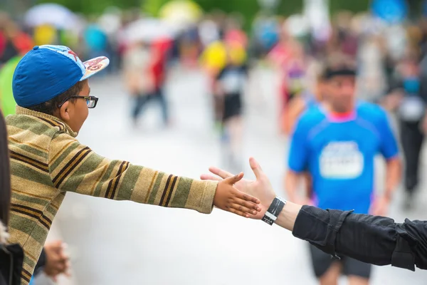 Happy young kid doing high fives and motivates the runners at AS — Stock Photo, Image