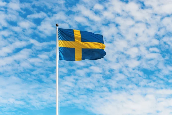 Svensk flagga vajande i vinden mot en blå himmel — Stockfoto