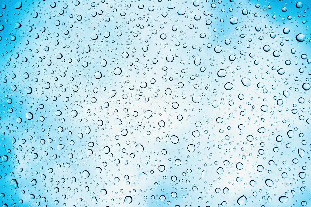 Water drops on glass with sky in background