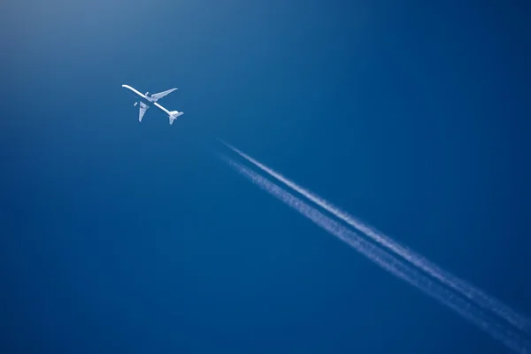 Airliner at high altitude with white condesation trails — Stock Photo, Image