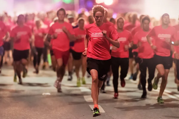 En fokuserad löpare i en av de många grupperna av midnatt kör — Stockfoto