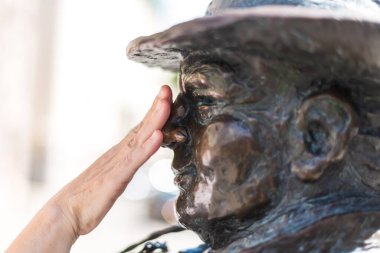 TALLINN, ESTONIA - JULY 11, 2022: The Lucky Chimney Sweeper statue in bronze with a woman hand at his nose.