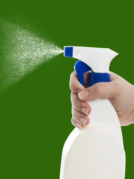 Mão com garrafa de spray de limpeza no verde — Fotografia de Stock