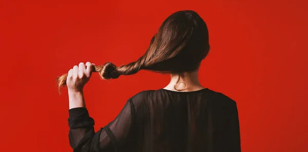 Брюнетка женщина тянет ее длинные волосы с узлом это — стоковое фото