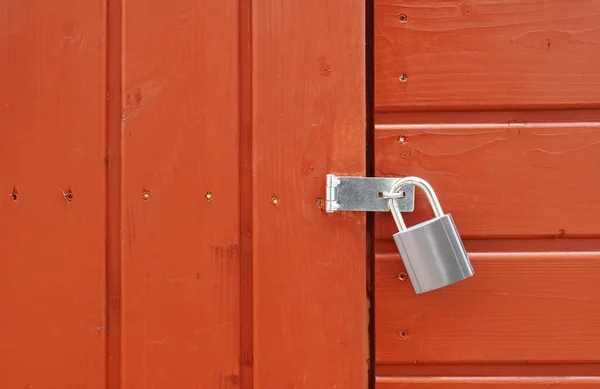 Padlock on locked door of wood cabin or wooden shed — стоковое фото