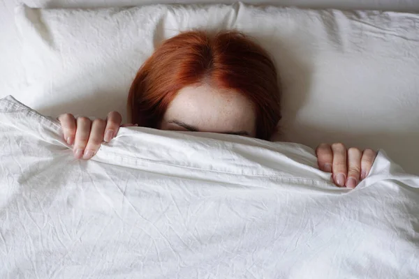 Woman hiding face from sunlight under bed cover — Stock Photo, Image