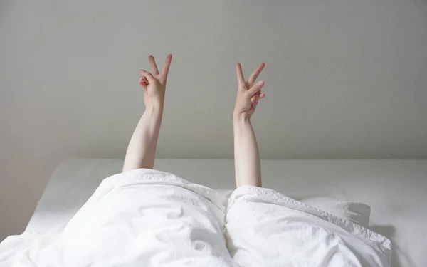 Žena ukazující klid nebo v rukou znamení při ležení v útulné posteli a skrývání pod přikrývkou — Stock fotografie