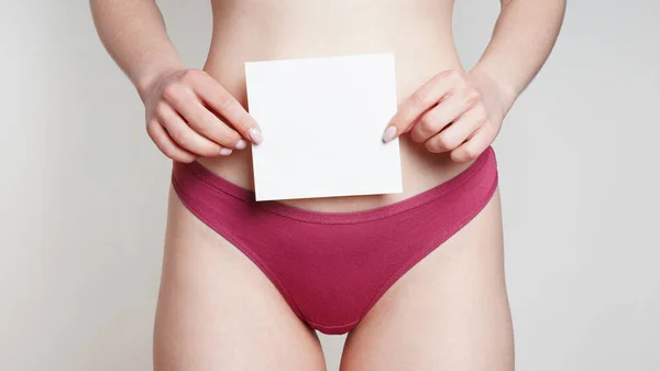 woman in panties holding empty sign with copy space over belly as womens health or gynecological disorder concept