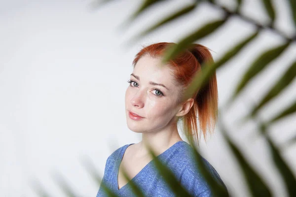 Retrato interior de mulher jovem baleada através de folhas de plantas — Fotografia de Stock