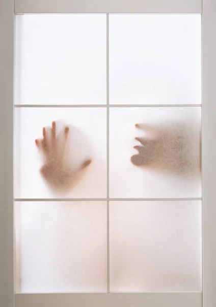 Silhouette of woman pressing hand and face against transparent screen — стоковое фото