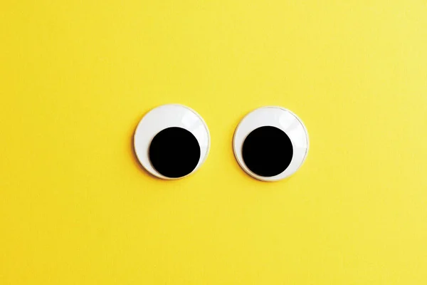 Paar Googly Augen Auf Gelbem Papier Hintergrund lizenzfreie Stockfotos