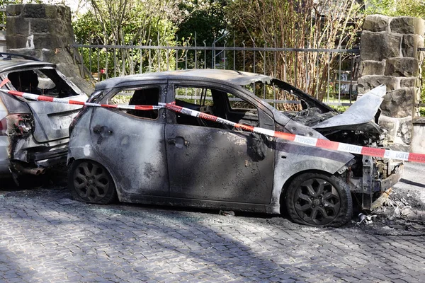 burnt out car wrecks behind police tape in residential city street in Germany