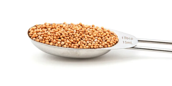 Mustard seeds measured in a metal tablespoon — Stock Photo, Image