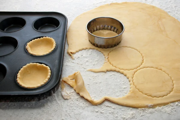 Teigkreise werden geschnitten und eine Brötchenform gefüllt, um Marmeladentörtchen zu machen — Stockfoto