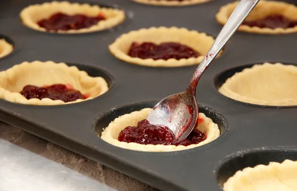 Closeup of jam tarts being filled with a teaspoon — Stock Photo, Image