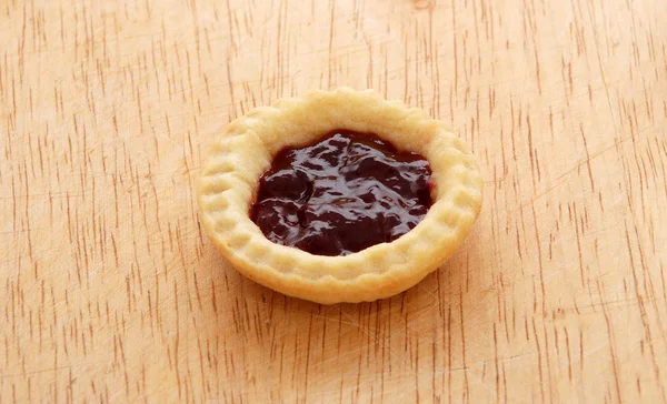 Single tasty jam tart on a wooden table — Stock Photo, Image