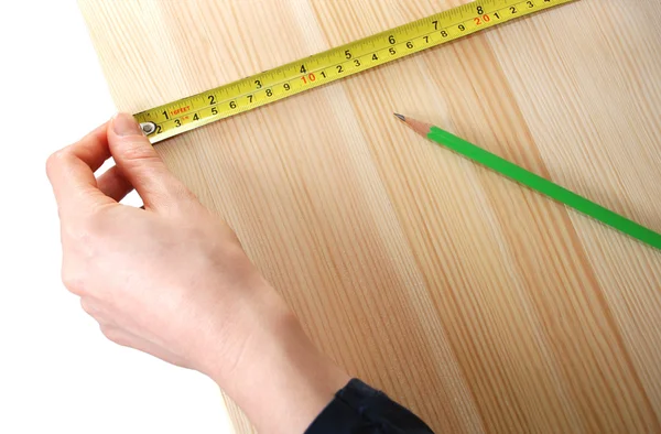 Het gebruiken van een stalen bandmaatregel op een houten bord tegen een witte bac — Stockfoto