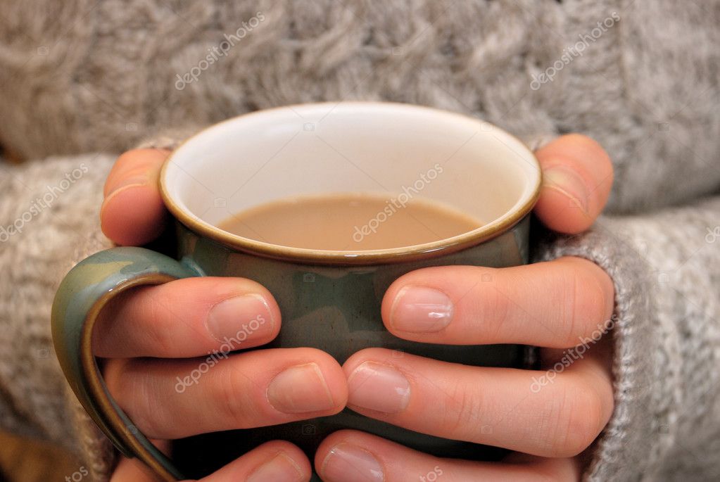 Two hands keeping warm, holding a hot cup of tea or coffee Stock Photo