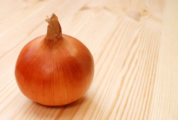 Cebola branca inteira em uma mesa de madeira — Fotografia de Stock