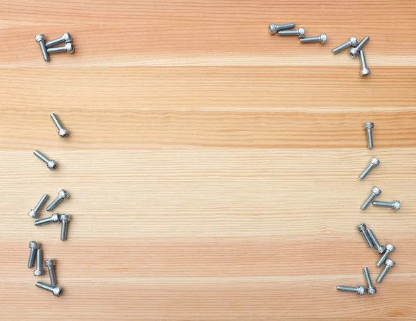 Socket head bolts as border on wood — Stock Photo, Image