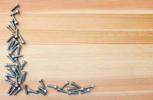 Tornillos de cabeza de zócalo como borde en forma de L sobre fondo de grano de madera — Foto de Stock