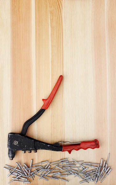 Metal pop rivets and a riveter on wood — Stock Photo, Image