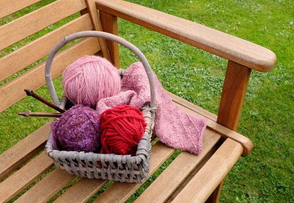 Basket of knitting and yarns on a bench — Stock Photo, Image