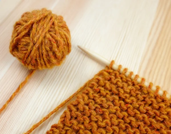 Närbild av strumpeband stitch stickning och orange ull — Stockfoto