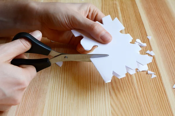 Using scissors to cut out a paper snowflake shape — Stock Photo, Image