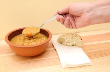 Eli ekmek rulo ve peçete ile çorba kaşığı tablosu üzerinde tutar.