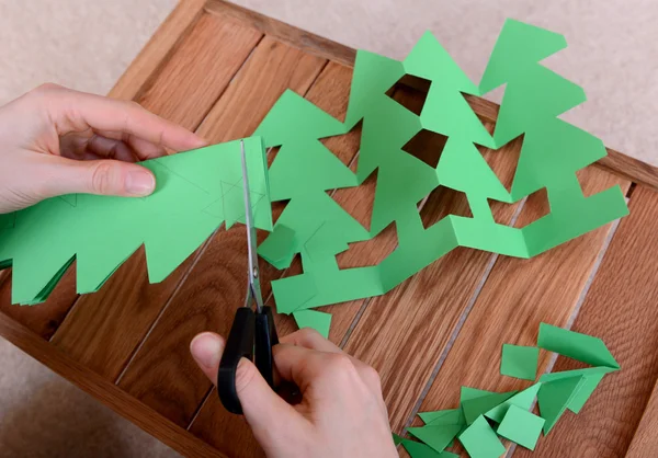 Cutting green card into a chain of Christmas trees — Stock Photo, Image