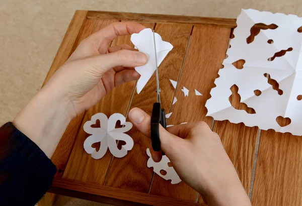 Vrouw papier sneeuwvlokken op een houten ambachtelijke tafel maken — Stockfoto