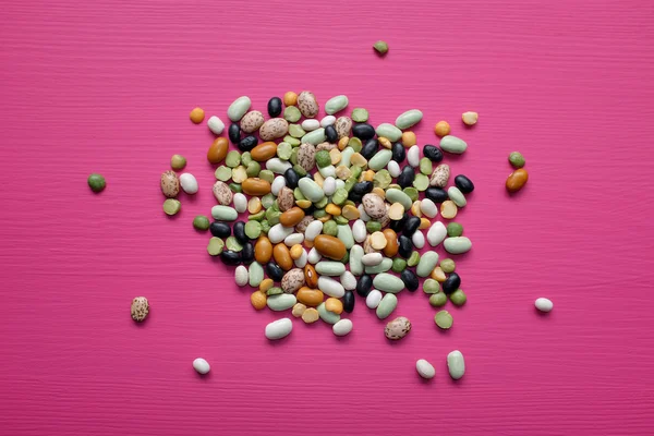 Mixed dried beans and peas on a pink background — Stock Photo, Image