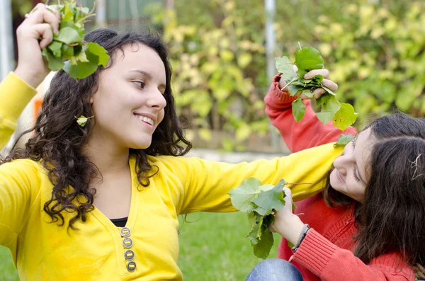 Dvě krásné šťastné děti hrát si s listy v zahradě — Stock fotografie