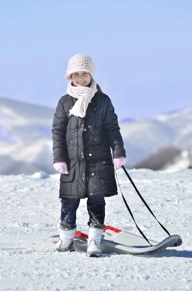 Inocent bambina vestita di bianco, treccia con la slitta sul paesaggio neve — Foto Stock