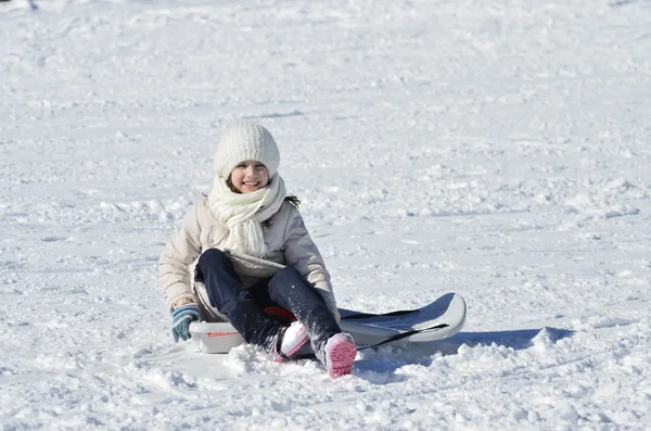 Inocent little girl white dressed, plaing with the sleigh on the snow landscape — Stock Photo, Image