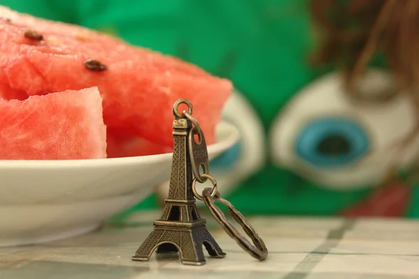 Souvenir in the form of the Eiffel Tower near the plate with watermelon