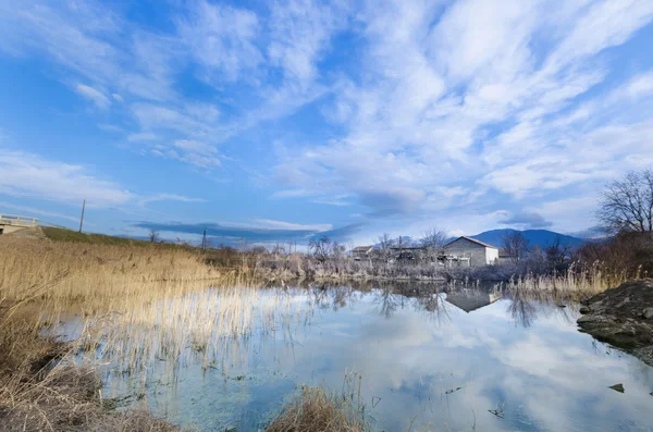 I träsket med säv och gamla hus på den klart molnig himmel — Stockfoto