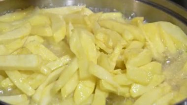 Fritöz içinde tahta spatula ile karıştırma patates kızartması closeup pan. yağda kaynar.