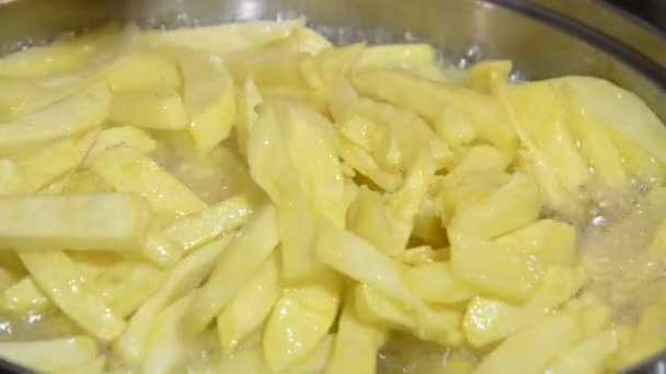 Перемешивание картошки фри с деревянной лопаткой в сковороде. Кипячение в масле . — стоковое видео