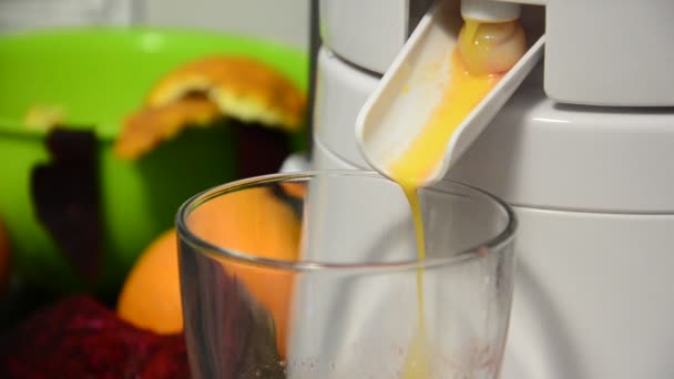 Glas vullen met verse healty oranje en rode bieten sap van juicer — Stockvideo