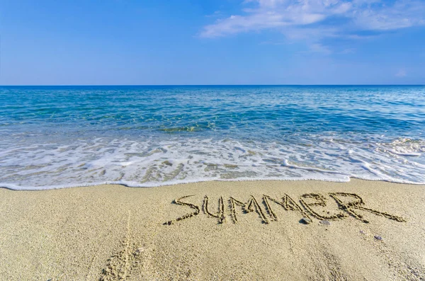 Palavra SUMMER desenhado na areia de uma praia — Fotografia de Stock