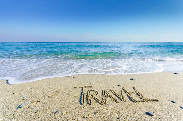 Palavra TRAVEL desenhado na areia de uma praia — Fotografia de Stock