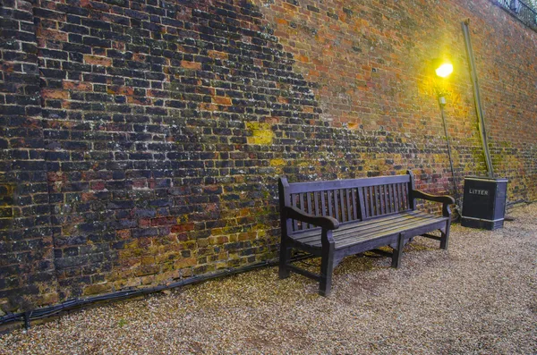 Old wooden benches in old alley with brick wall — Stock Photo, Image