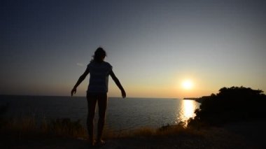Kızın rahatlatıcı ve Okyanusu günbatımı üzerinde egzersiz taking