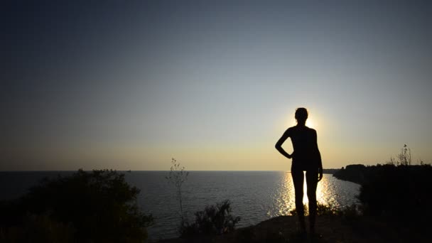 Silhouet van meisje uit te oefenen op een zonsondergang oceaan strand — Stockvideo