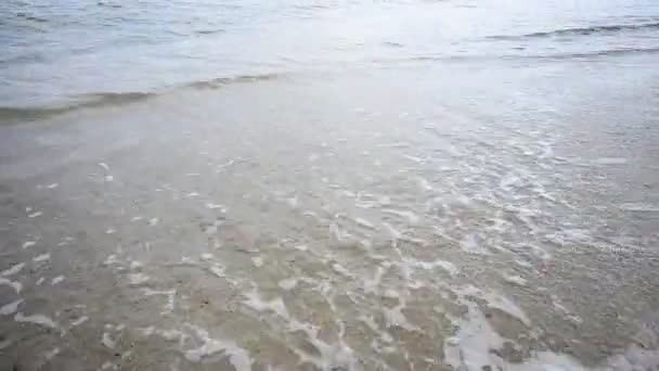 Κορίτσι περπατά και αφήνει ίχνη στην άμμο βρέχεται από τα κύματα του ωκεανού — Αρχείο Βίντεο