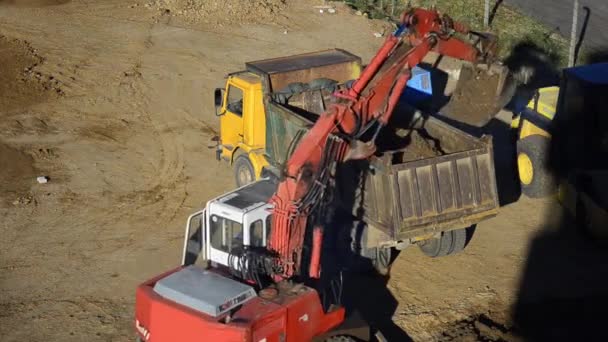 Передний погрузчик загружает грузовик с рытьем земли — стоковое видео